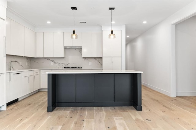 kitchen with tasteful backsplash, light countertops, white cabinets, and light wood finished floors