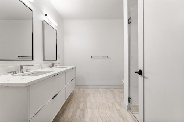 bathroom featuring a stall shower, a sink, baseboards, and double vanity