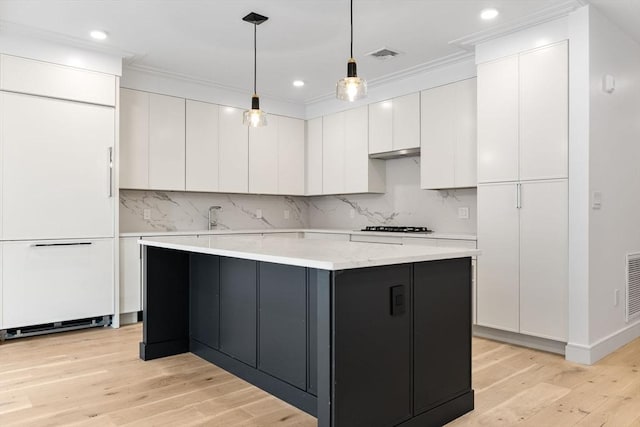 kitchen featuring visible vents, white cabinets, light wood-style flooring, a center island, and light countertops