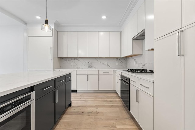 kitchen featuring light wood finished floors, tasteful backsplash, white cabinets, stainless steel gas cooktop, and black oven