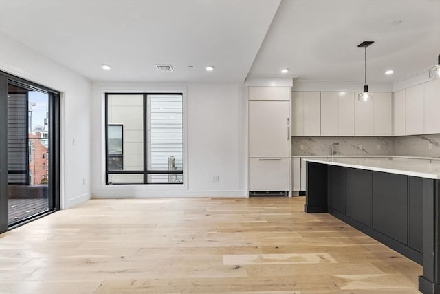 kitchen with visible vents, white cabinetry, light wood-style floors, light countertops, and backsplash