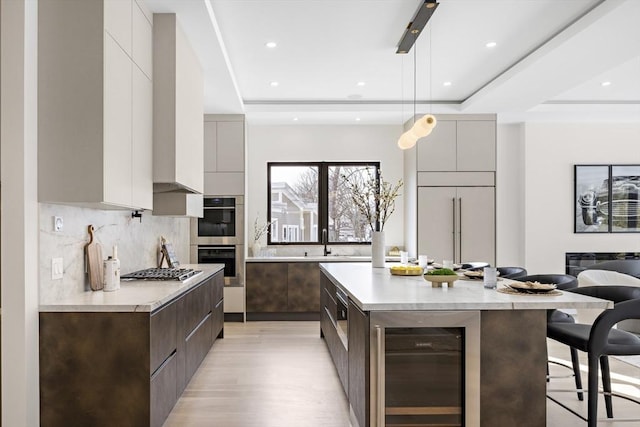 kitchen featuring beverage cooler, a spacious island, light countertops, modern cabinets, and decorative light fixtures