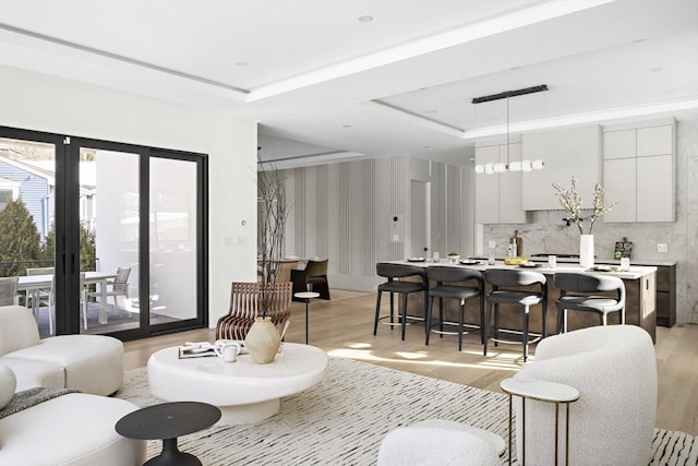 living area featuring light wood-style floors and a tray ceiling