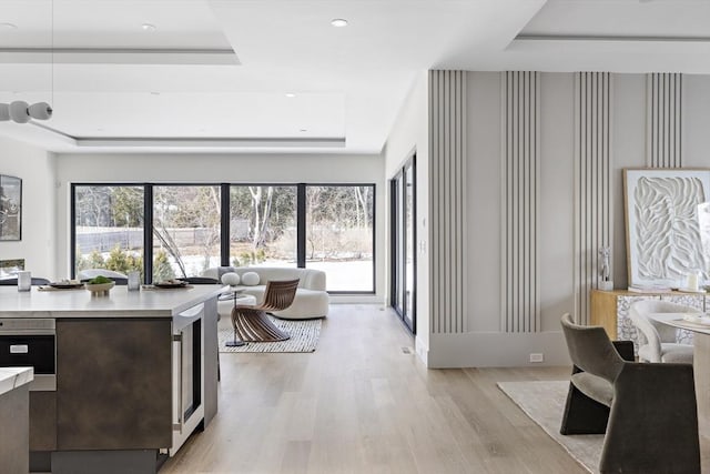 interior space with modern cabinets, a tray ceiling, light countertops, light wood-style floors, and recessed lighting