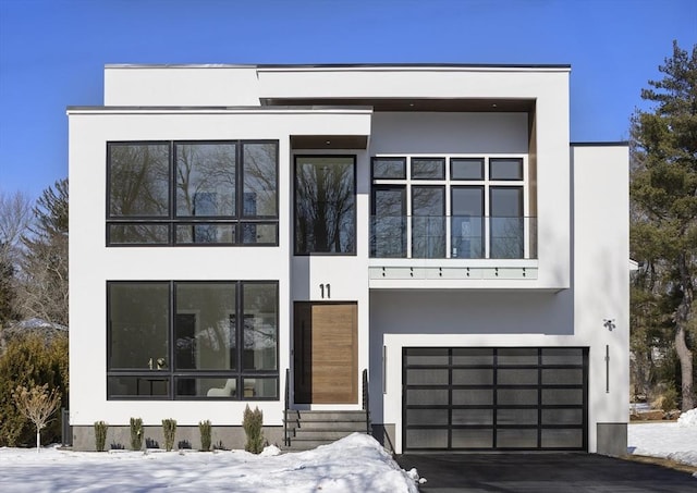 contemporary home with a garage, entry steps, driveway, and stucco siding