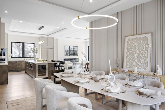 dining area with light wood-style flooring, wine cooler, a tray ceiling, and recessed lighting