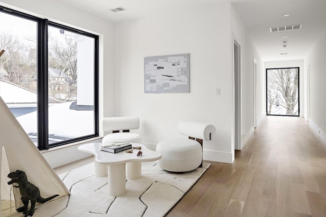 sitting room with light wood-style floors, baseboards, and visible vents