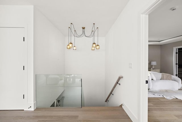 interior space with a chandelier, an upstairs landing, and wood finished floors