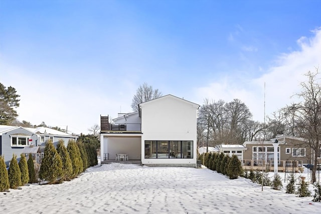 snow covered back of property with a residential view, fence, and stucco siding