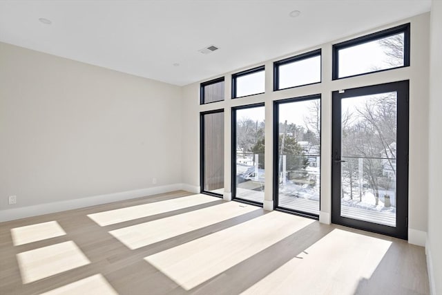 empty room featuring visible vents, light wood-style flooring, and baseboards