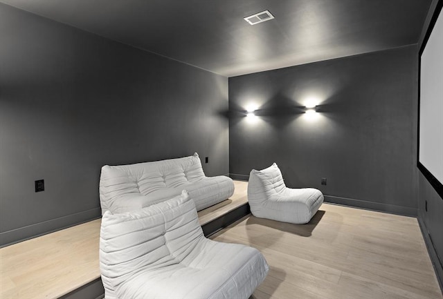 home theater featuring light wood-type flooring, visible vents, and baseboards