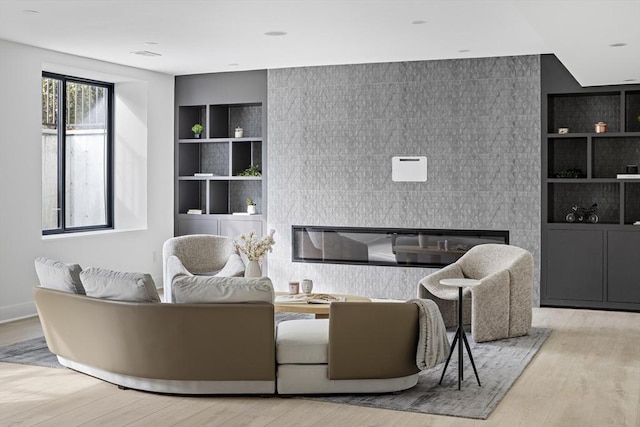 living area with light wood-style flooring, built in shelves, and a tiled fireplace