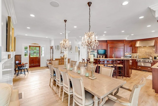 dining room featuring crown molding, a chandelier, and light wood-type flooring