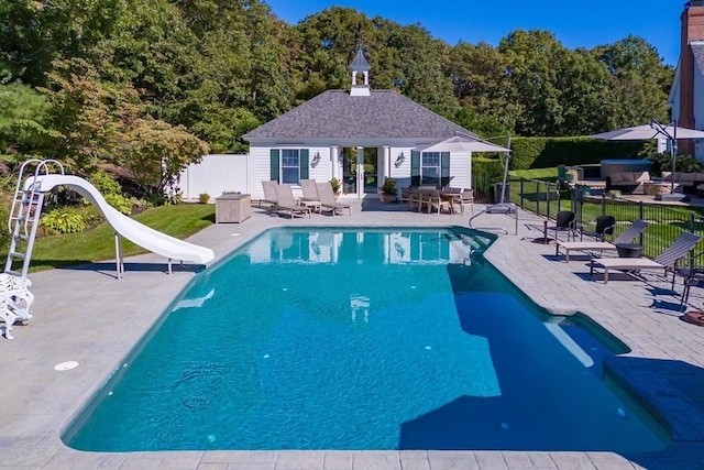 view of swimming pool featuring an outbuilding, a patio, and a water slide