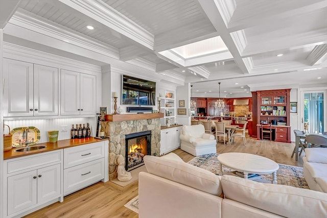 living room featuring ornamental molding, a fireplace, sink, and beam ceiling