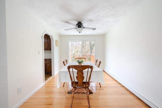 dining area with baseboards, ceiling fan, baseboard heating, and light wood finished floors