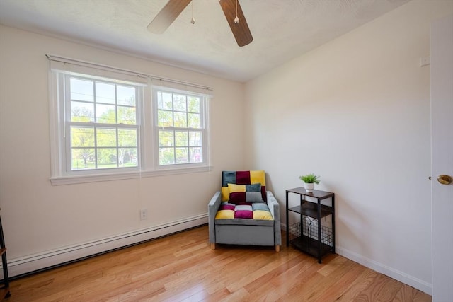 sitting room featuring baseboards, ceiling fan, baseboard heating, and wood finished floors