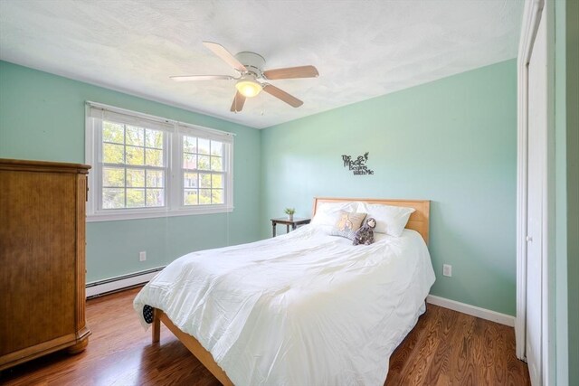 bedroom featuring baseboards, ceiling fan, baseboard heating, and wood finished floors