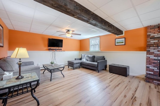 living room with ceiling fan, wainscoting, wood finished floors, and a paneled ceiling