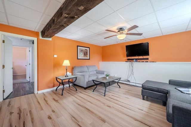living room featuring baseboards, a ceiling fan, a drop ceiling, and wood finished floors