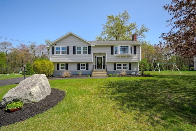 raised ranch featuring a chimney and a front yard