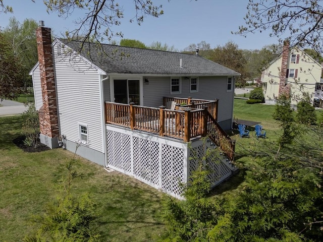 rear view of house featuring roof with shingles, a yard, a chimney, and a deck