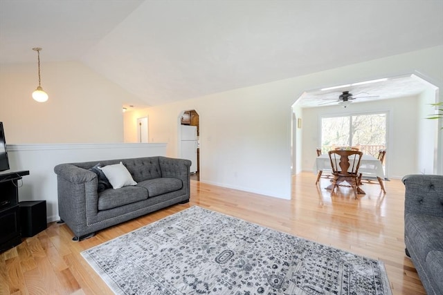 living room with arched walkways, ceiling fan, lofted ceiling, and light wood finished floors