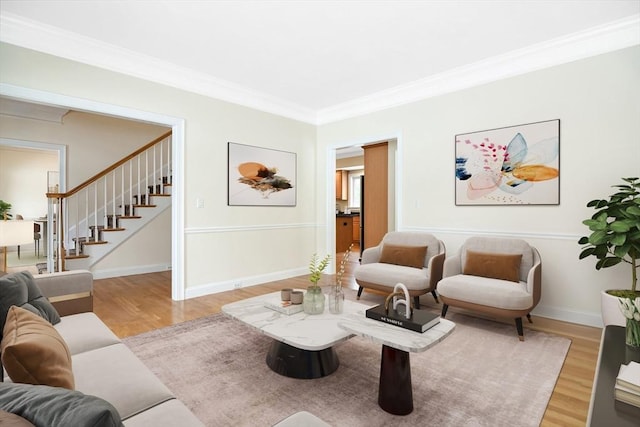 living room with light wood-type flooring, baseboards, ornamental molding, and stairs