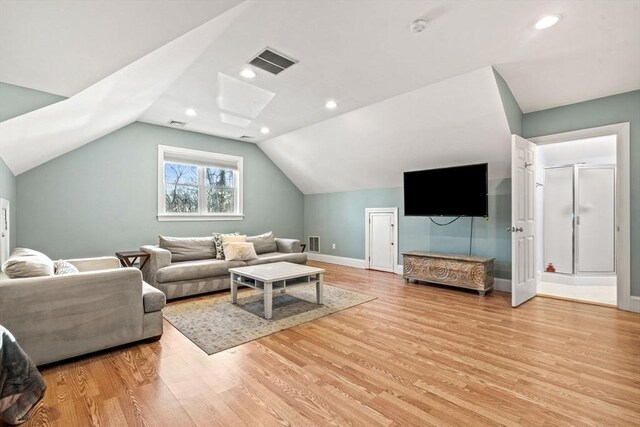 living room featuring lofted ceiling, baseboards, visible vents, and light wood finished floors