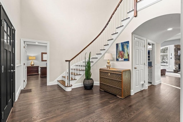entrance foyer with a towering ceiling, dark wood-style floors, stairway, and visible vents