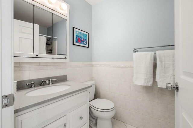 full bathroom with curtained shower, toilet, a wainscoted wall, vanity, and tile walls
