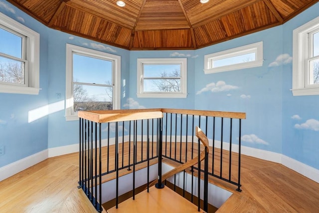 stairs featuring wood finished floors, wood ceiling, and baseboards