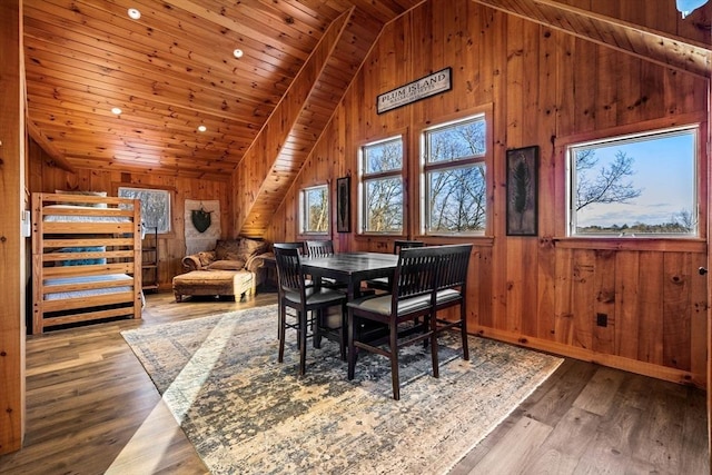 dining area with wooden walls, baseboards, wooden ceiling, wood finished floors, and vaulted ceiling