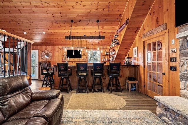 living room featuring wood ceiling, wood finished floors, stairs, a bar, and wood walls