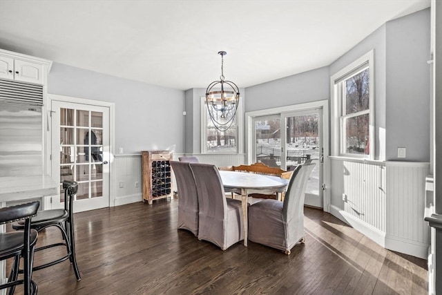 dining room with dark wood-style floors, an inviting chandelier, and wainscoting
