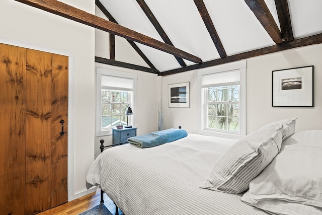 bedroom featuring light hardwood / wood-style floors, beamed ceiling, and high vaulted ceiling