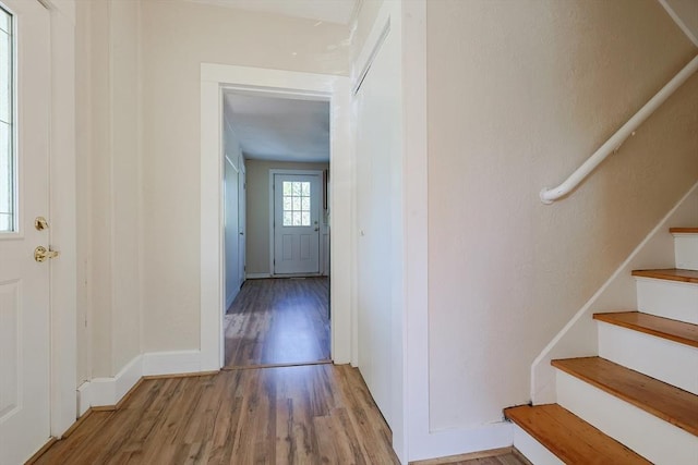 hall featuring wood finished floors, stairway, and baseboards