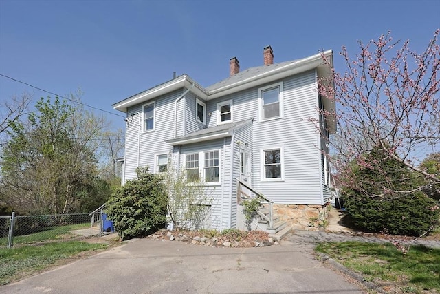 view of front facade featuring fence and a chimney