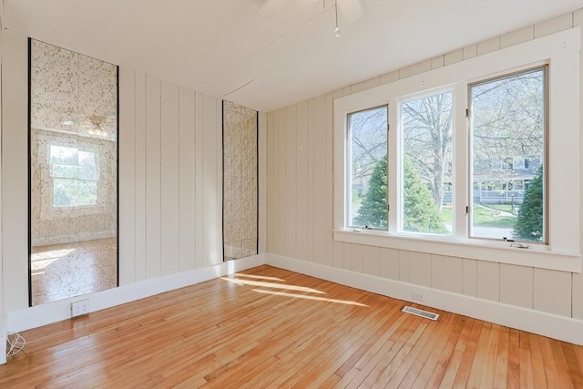 spare room featuring hardwood / wood-style floors, healthy amount of natural light, and baseboards