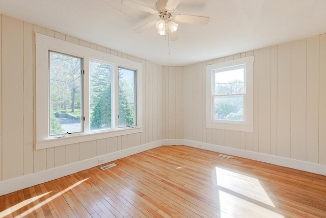 empty room with wood-type flooring, healthy amount of natural light, baseboards, and ceiling fan