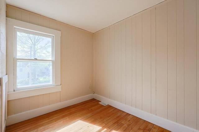 spare room with light wood finished floors, baseboards, and wood walls