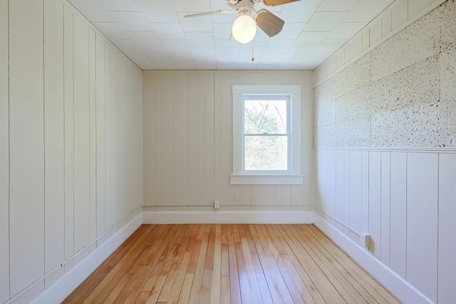 spare room with light wood-type flooring, ceiling fan, and baseboards