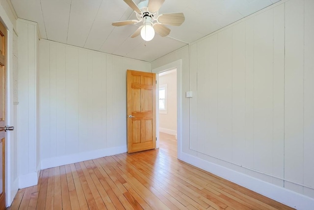 spare room featuring light wood finished floors, baseboards, and ceiling fan