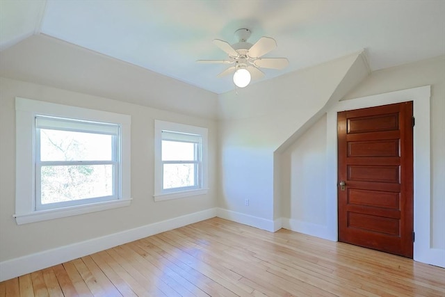 additional living space featuring baseboards, light wood-style floors, a ceiling fan, and vaulted ceiling