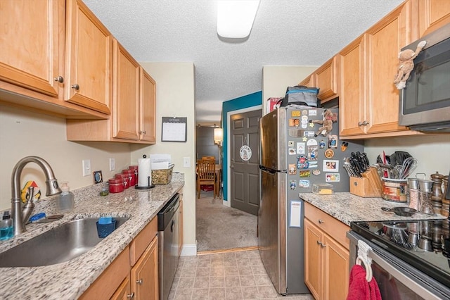 kitchen with a textured ceiling, a sink, stainless steel appliances, and light stone countertops