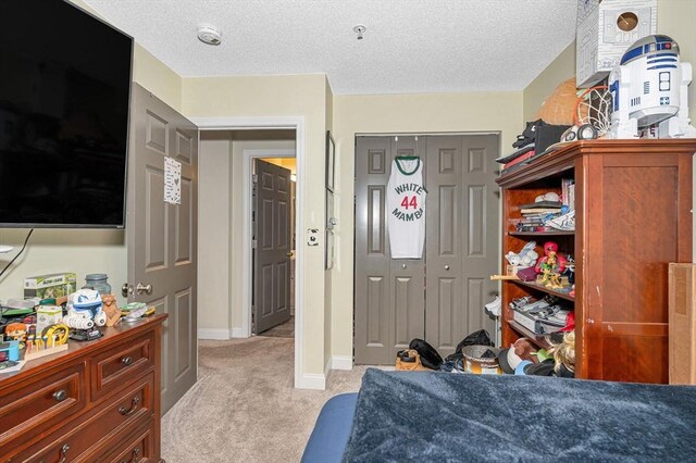 bedroom with baseboards, light carpet, a textured ceiling, and a closet