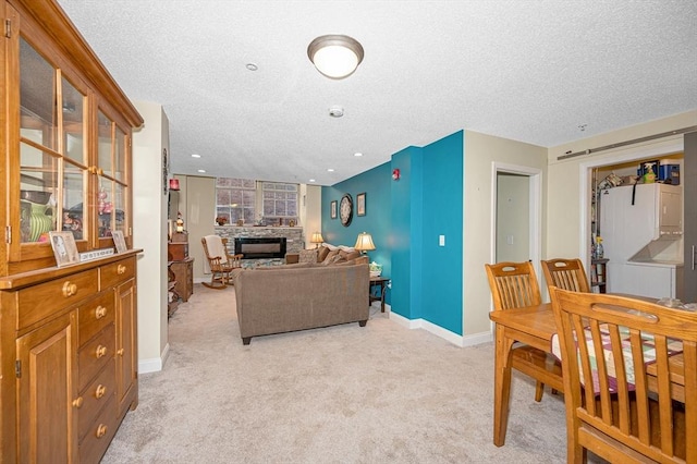 living room with baseboards, light carpet, a textured ceiling, and a stone fireplace