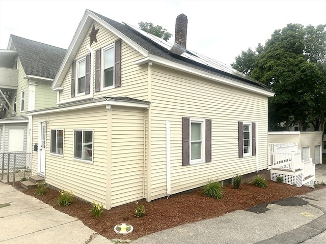 55 Mendon St, Worcester, MA 01604 - view of property exterior featuring a chimney, solar panels, and a shingled roof