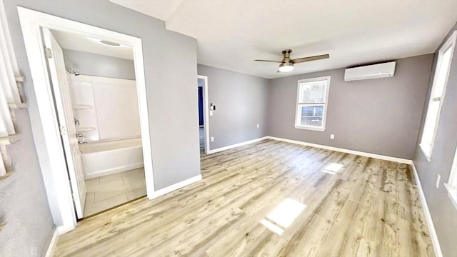 55 Mendon St, Worcester, MA 01604 - unfurnished bedroom with an AC wall unit, light wood-style flooring, baseboards, connected bathroom, and a ceiling fan