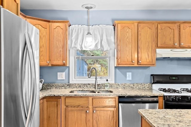 kitchen featuring appliances with stainless steel finishes, range hood, a sink, light stone countertops, and decorative light fixtures